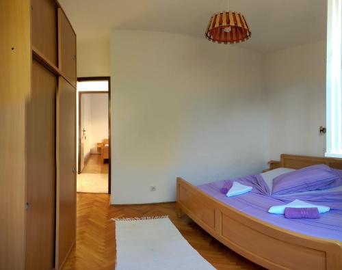 a bedroom with a bed with purple sheets at Apartmani Sandro in Ivan Dolac