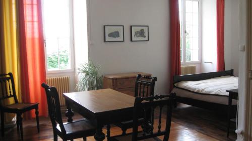 a dining room with a table and a bed and windows at Le Petit Bois in Château-la-Vallière