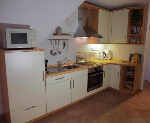 a kitchen with white cabinets and a microwave and a sink at An´t Möhlen in Carolinensiel