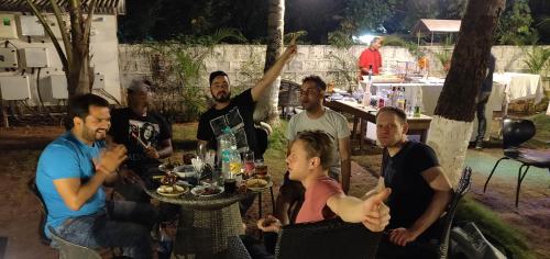 a group of people sitting around a table at night at Bedrock Boutique Hostel in Baga
