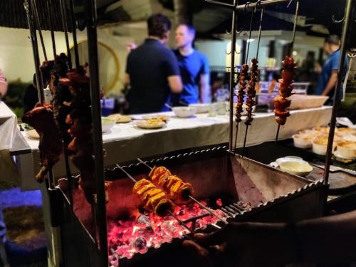 a grill with food on it with people in the background at Bedrock Boutique Hostel in Baga