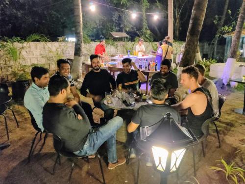 a group of men sitting around a table at night at Bedrock Boutique Hostel in Baga