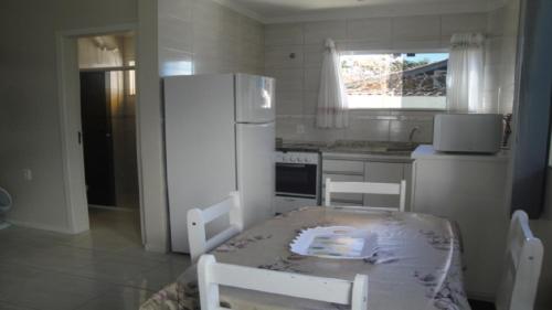 Il comprend une cuisine équipée d'une table et d'un réfrigérateur blanc. dans l'établissement apartamentos em ponta das canas, à Florianópolis