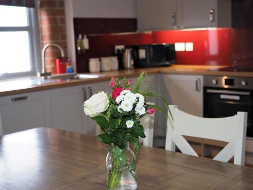 a vase of flowers on a table in a kitchen at Nellies Shed, Wolds Way Holiday Cottages, 3 bed spacious cottage in Cottingham