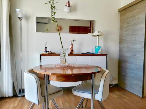 une table de salle à manger et des chaises avec un vase dessus dans l'établissement STUDIO PORT D’HYÈRES VUE MER ET ÎLES DE PORQUEROLLES ET PORT-CROS, à Hyères