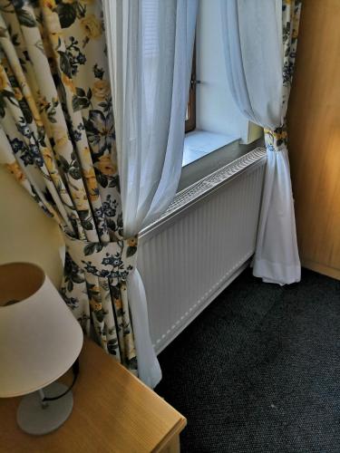 a room with a window with a curtain and a chair at Penzion u lípy in Jestřebí