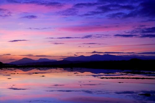 a sunset over a lake with mountains in the background at Appin Holiday Homes -Caravans, Lodges, Shepherds Hut and Train Carriage stays in Appin
