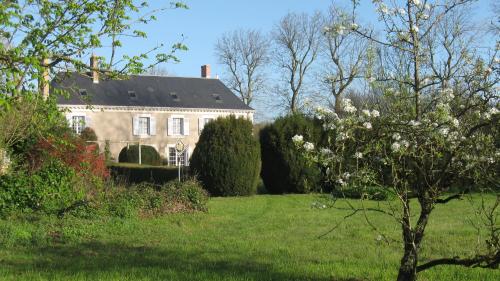 a large house in a field with trees and bushes at Le Petit Bois in Château-la-Vallière