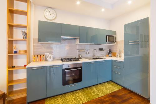 una cucina con armadi blu e un orologio sul muro di Naima Sea View Design Apartment By HouseinNaples a Napoli