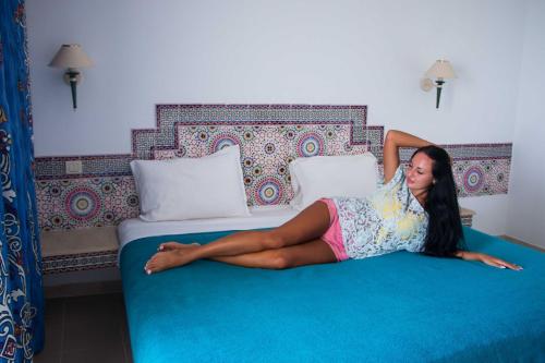 a woman laying on top of a bed at Hotel Dreams Beach in Hammam Sousse