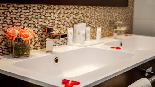 a bathroom with two sinks and a vase of orange roses at AZ Hôtels Zeralda in Zeralda