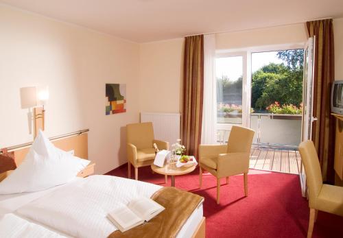 a hotel room with a bed and a table and chairs at Landhotel Hermannshöhe in Legden
