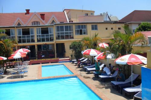 a hotel with a swimming pool with umbrellas and chairs at Hôtel - Appartement meublé " LES FLOTS BLEU " in Antananarivo