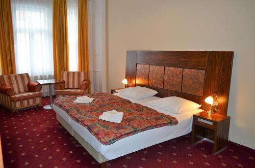 a hotel room with two beds and a lamp at Hotel Palacky in Karlovy Vary
