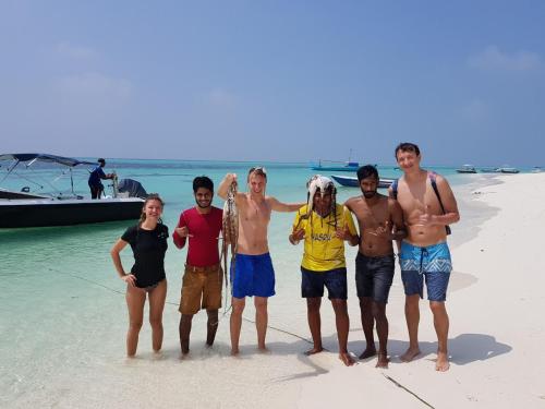 a group of young men standing on a beach at Thoddoo Beach Holiday in Thoddoo