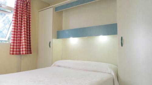 a white bedroom with a bed and a window at Bungalows Bahia de la Plata in Zahara de los Atunes