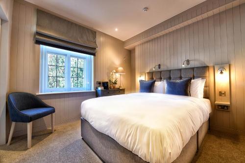 a bedroom with a large bed and a blue chair at The Bridge Pub & Rooms in London