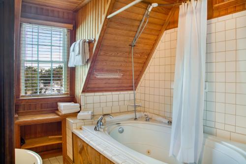 baño con bañera, aseo y ventana en The Castle B&B on Silver Lake, en Ocracoke
