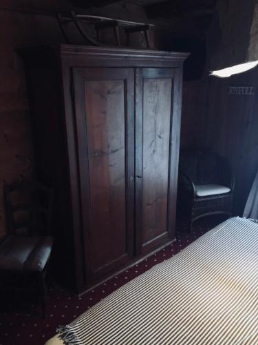 a bedroom with a wooden cabinet next to a bed at Le Coin Savoyard in Combloux