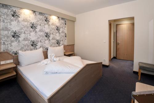 a bedroom with a large bed with white sheets at Golf & Skipension Krug in Haus im Ennstal