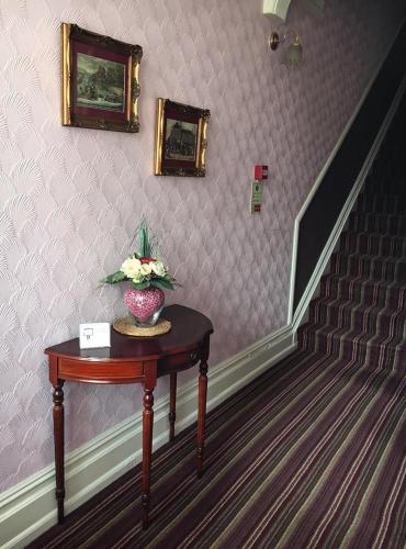 a staircase with a table with a vase of flowers on it at Glenmore Guesthouse in Southampton