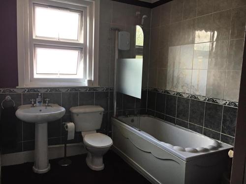 a bathroom with a sink and a tub and a toilet at Glenmore Guesthouse in Southampton