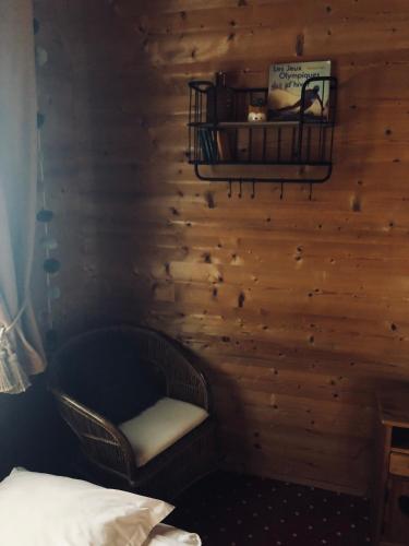 a bedroom with a chair and a wooden wall at Le Coin Savoyard in Combloux