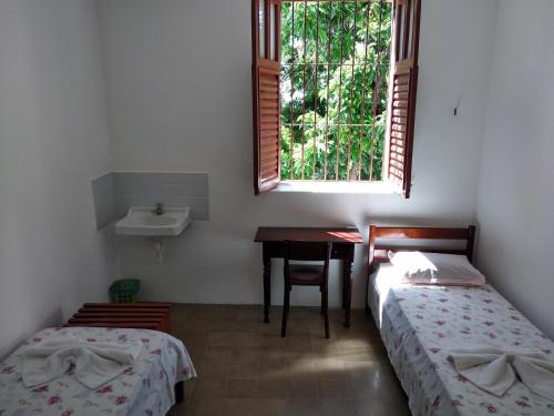 a room with two beds and a sink and a table at Pousada Convento da Conceição in Olinda