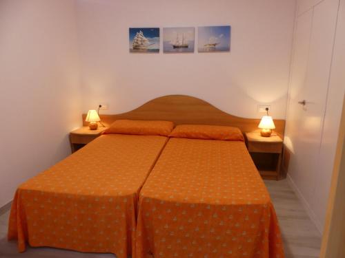 1 dormitorio con 1 cama con sábanas de color naranja y 2 lámparas en Zeus Alexis, en Salou