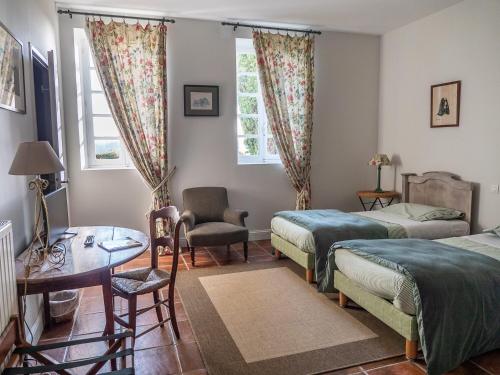 a bedroom with two beds and a table and a chair at Le Peyret in Serres-Castet