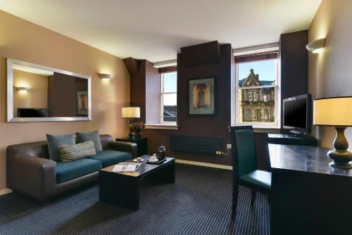 a living room with a couch and a tv at Fraser Suites Glasgow in Glasgow
