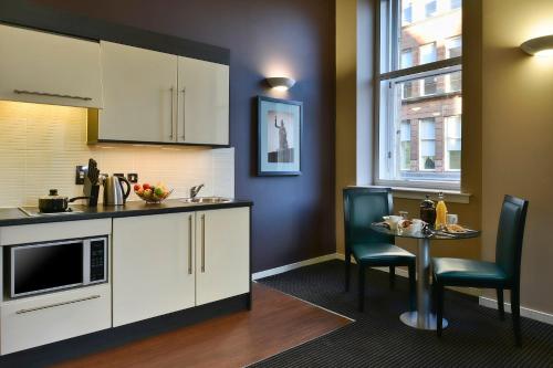 a kitchen with a table with chairs and a sink at Fraser Suites Glasgow in Glasgow