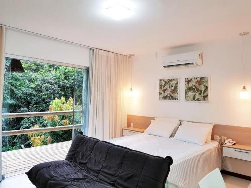 1 dormitorio con cama y ventana grande en Villas Pratagy Resort, en Maceió