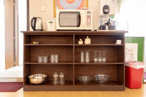 a shelf in a kitchen with a microwave at Shaligram Hotel in Pātan