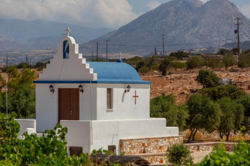 a small white church with a blue roof and a cross at Sun and Moon Villas in Aliko Beach