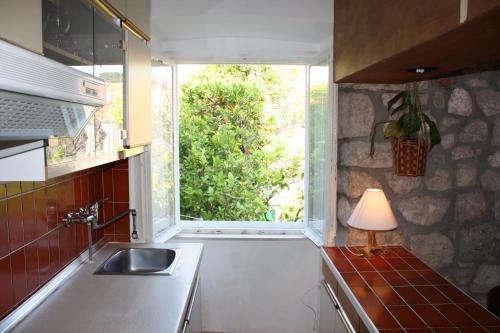 cocina con fregadero y ventana con lámpara en Apartment Naval en Dubrovnik