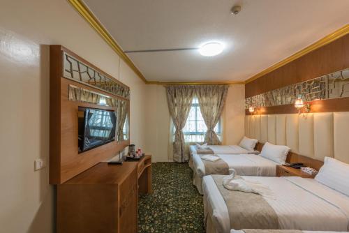 a hotel room with two beds and a television at Grand Zowar Hotel in Medina