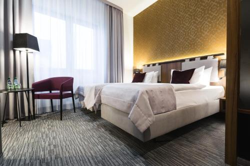 a hotel room with a large bed and a chair at Best Western Hotel Mariacki Katowice in Katowice