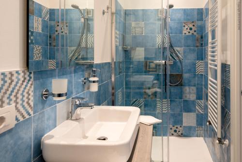 a blue tiled bathroom with a sink and a shower at La Meridiana in Piacenza