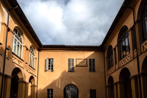 a building with arches and windows and a cloudy sky at La Meridiana in Piacenza