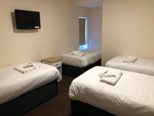 a room with three beds and a flat screen tv at Minworth Lodge in Minworth
