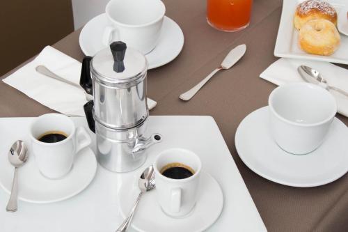 a table with white cups and saucers of coffee at Hotel Santa Brigida in Naples