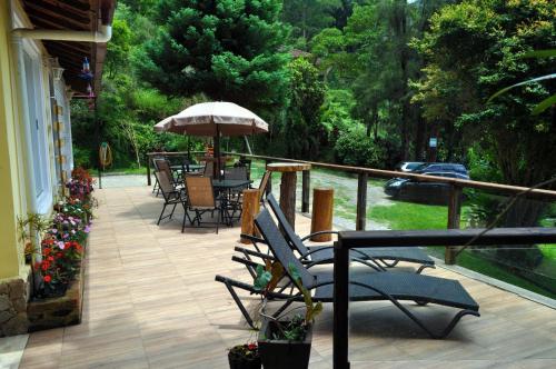 un patio con sedie e ombrellone su un balcone di Pousada Alto do Vale a Nova Friburgo