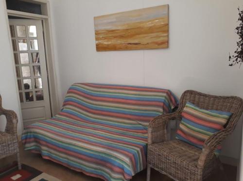 a wicker chair with a colorful striped blanket sitting next to a wicker chair at Flat in historic neighbourhood in Lisbon