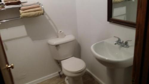 a white bathroom with a toilet and a sink at Tarragon Motel in Marinette