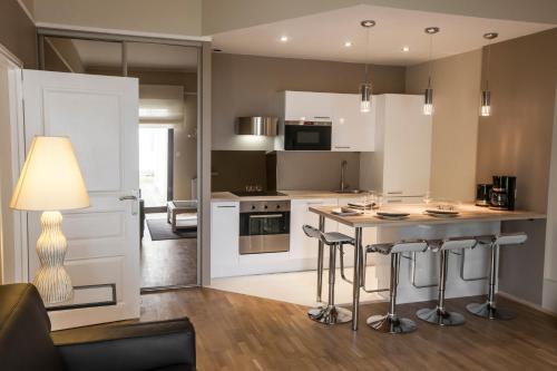 a kitchen with white cabinets and a island with bar stools at Appartement Gerland - Centre historique - in Dijon