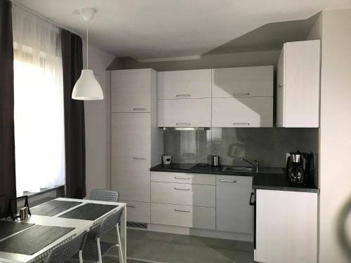 a kitchen with white cabinets and a table with chairs at Apartament koloru morza - Turkus in Łeba