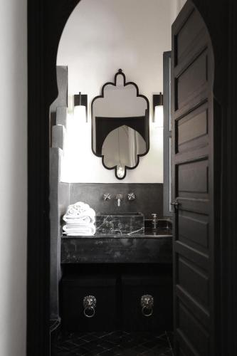 a black and white bathroom with a sink and a mirror at Riad Dar Bahi in Marrakesh