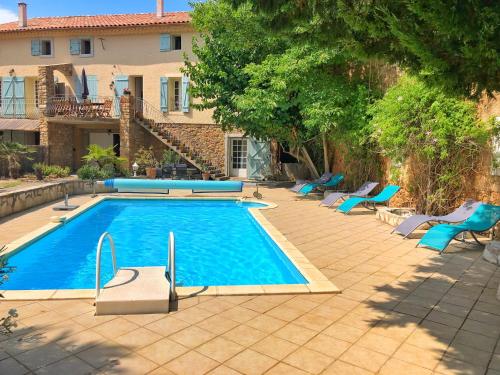 una piscina con sillas azules y una casa en Pradines, en Saint-André-de-Roquelongue
