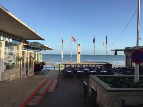 un edificio con tavoli e sedie sulla spiaggia di Maison de pêcheur 30m de la plage a Luc-sur-Mer